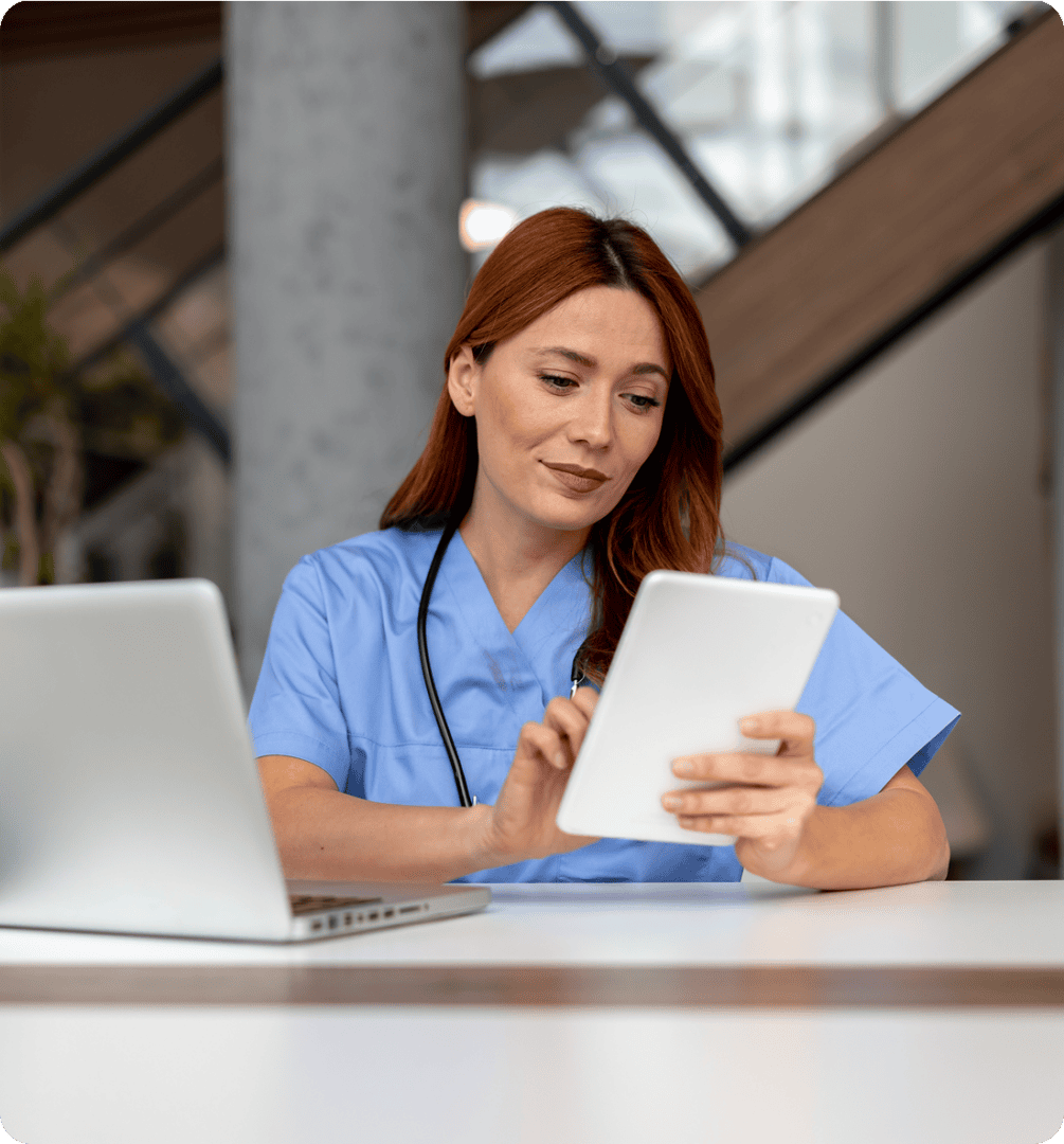Nurse using tablet at a desk.