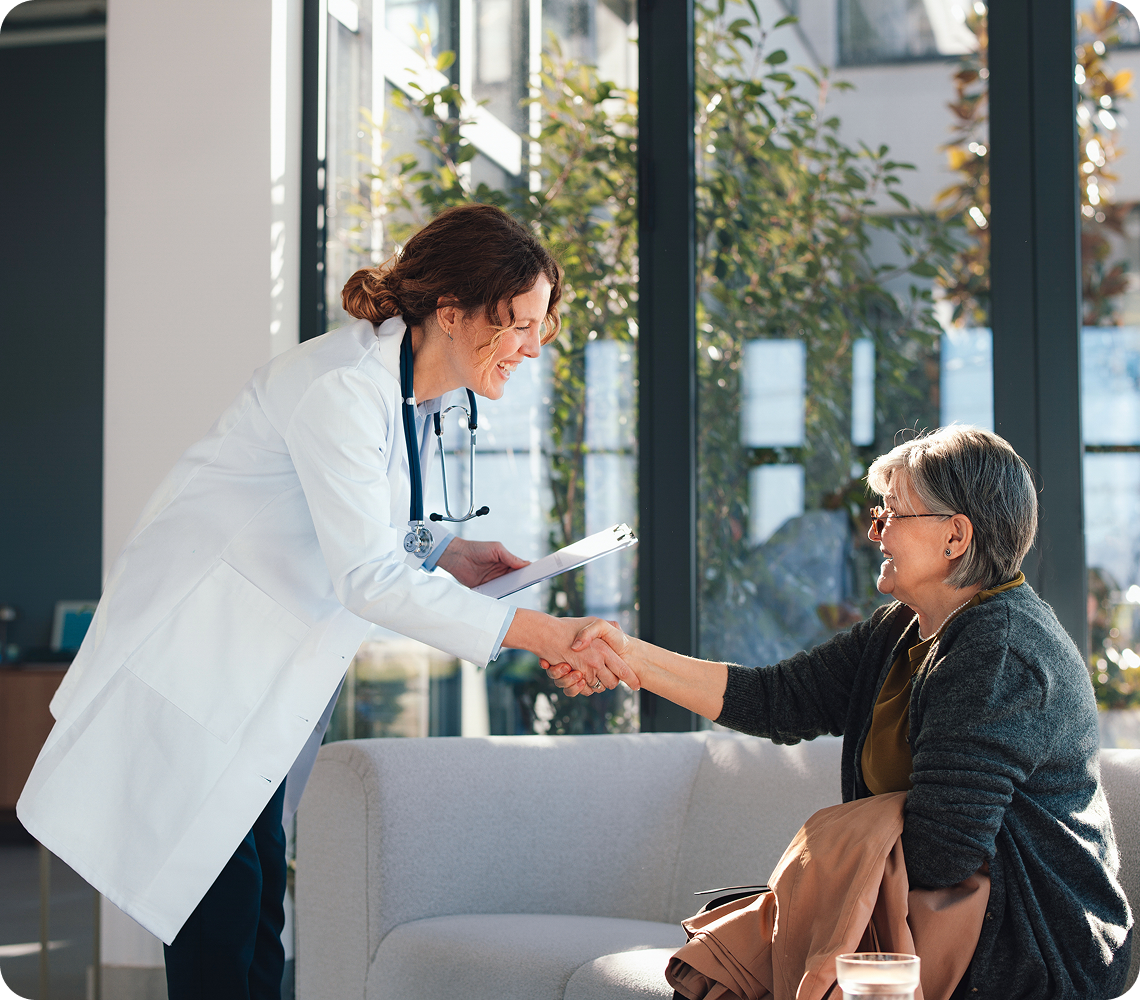 Doctor and patient shaking hands in office.