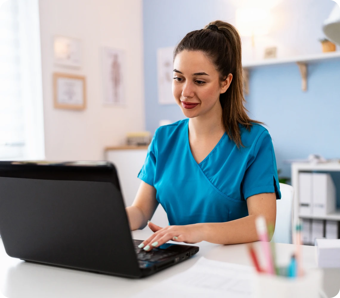 Nurse working on laptop in office.